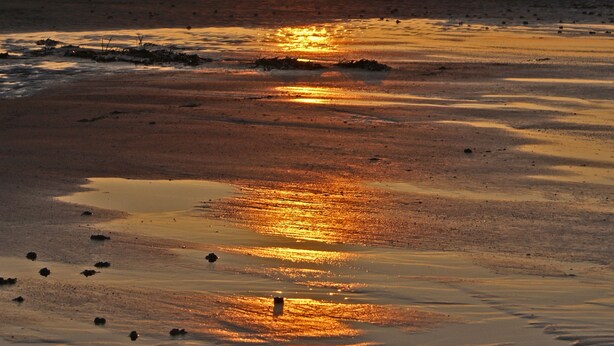 A beach at sunset with the sun reflecting on the water. - Aldersyde Bed and Breakfast (Whitby)