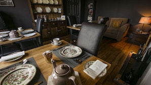 A dining area with a wooden table set for tea, surrounded by black leather chairs. - Aldersyde Bed and Breakfast (Whitby)