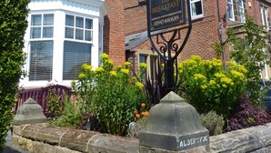 A traditional brick building with a sign for 'Aldersyde Bed and Breakfast' and a stone wall with a metal plaque reading 'Aldersyde'. - Aldersyde Bed and Breakfast (Whitby)