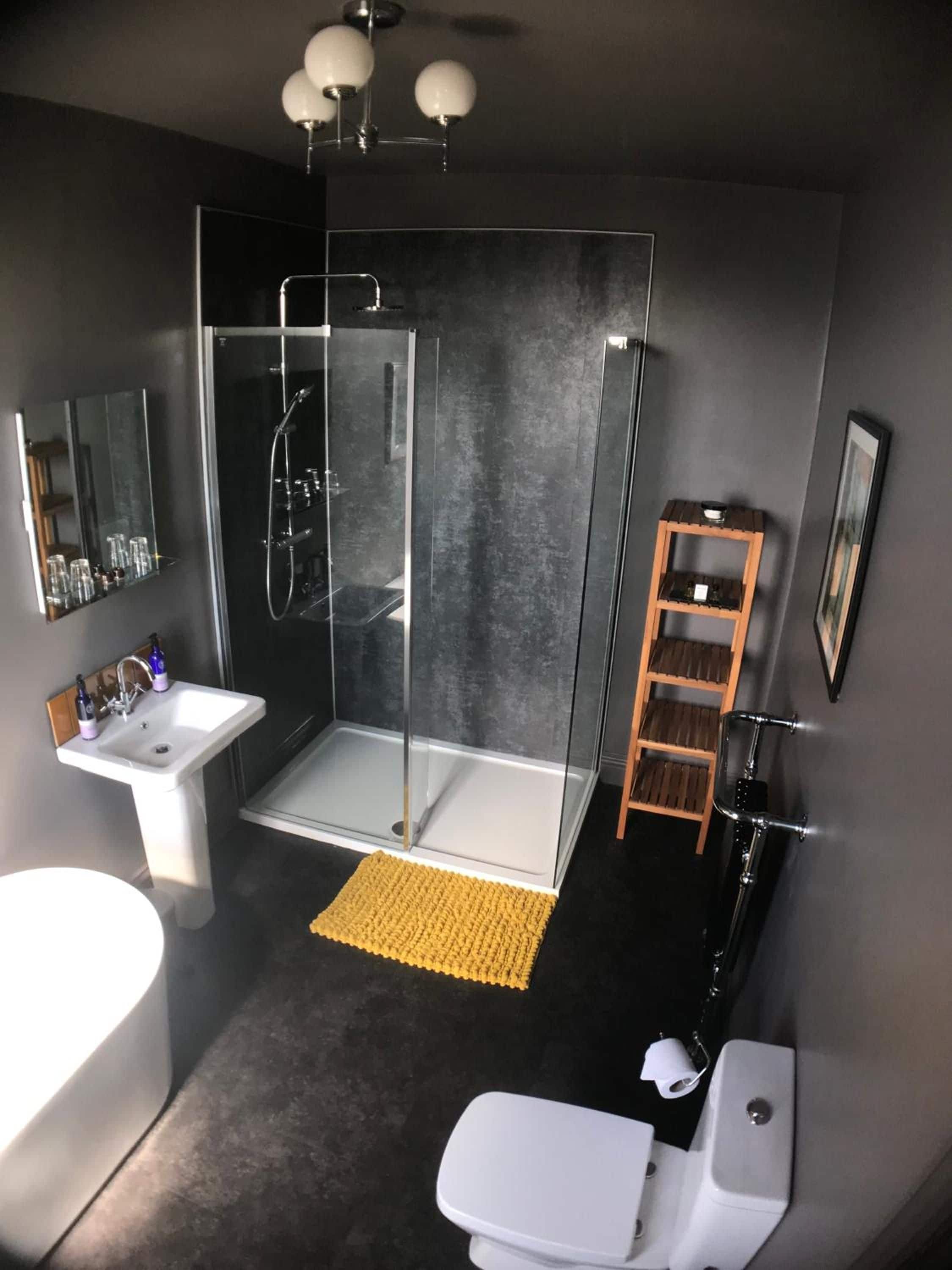A modern bathroom with a glass-enclosed shower, a white sink, and a toilet.