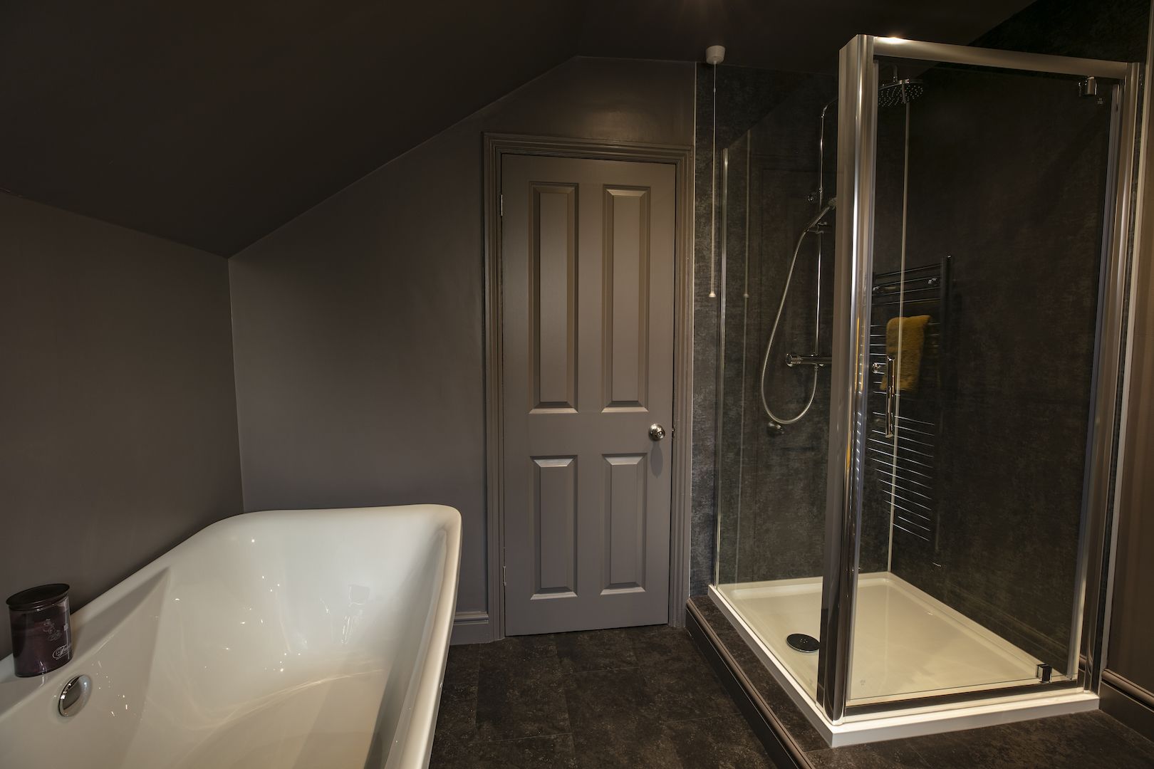 A bathroom with a bathtub, a shower, and a door.