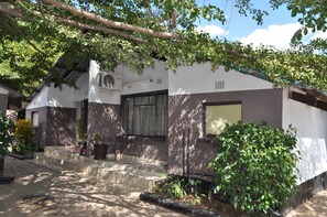 Una casa con una escalera de piedra que conduce a la entrada, rodeada de vegetación y un cielo despejado.