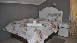 A bedroom with a bed, a nightstand, and a bedside table. - Willu Executive Lodge (Livingstone)