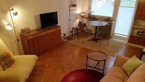 Ett mysigt vardagsrum med en soffa, en röd träningsboll, ett litet bord och en tv som står på ett träskåp.