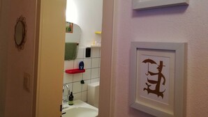 Ett badrum med handfat, spegel och en inramad tavla på väggen.