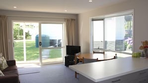 Ett modernt vardagsrum med en soffa, en tv, ett matbord och en köksdel med en köksbänk och skåp.