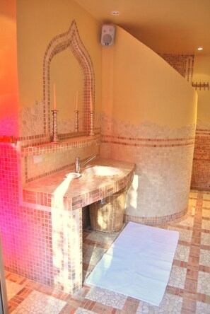 A bathroom with a mosaic tile design, a sink with a mirror, and a bathtub.