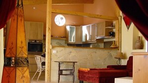 A cozy living room with a fireplace, a dining area with a table and chairs, and a kitchen with wooden cabinets and a built-in oven. - Vacation home with pool in a beautiful country location with sea views Wifi included (Santa Cruz de Tenerife)