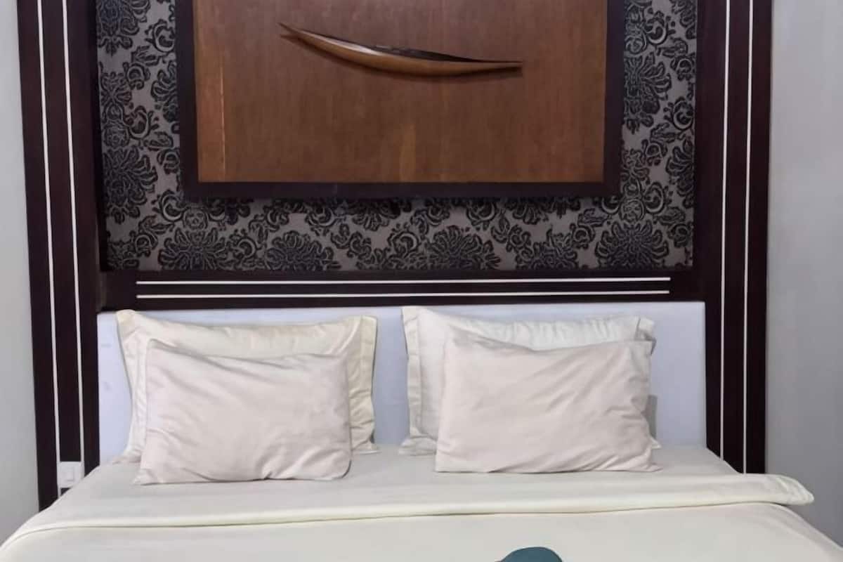 Ein Bett mit Kopfteil, zwei Kissen und einem Holzgegenstand darüber.