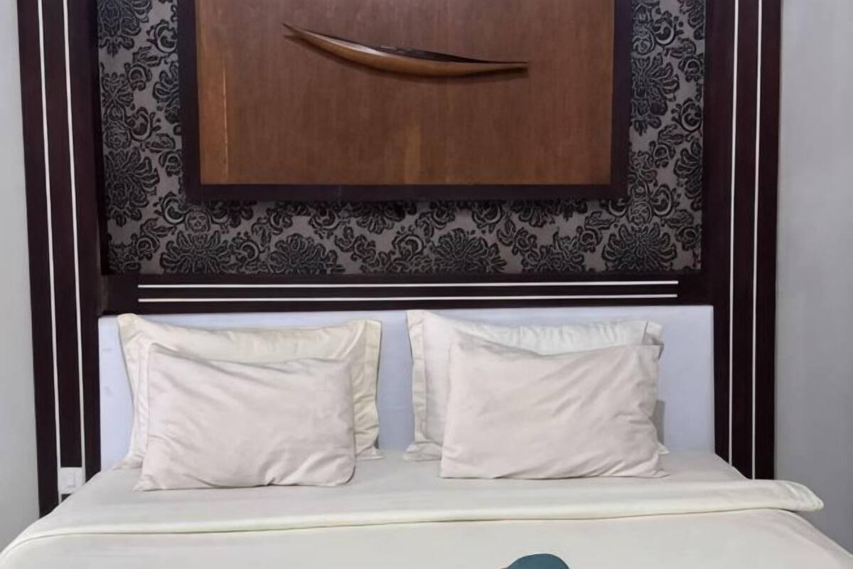 A bed with a headboard, two pillows, and a wooden object above the headboard.