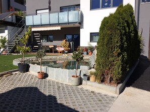 A modern building with a rooftop terrace, outdoor seating, and a small water feature. - Apartment 2-5 people - Apartment Schranz (Kaunerberg)