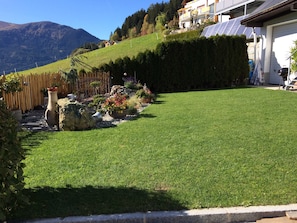A well-maintained lawn with a wooden fence, potted plants, and a stone feature. - Apartment 2-5 people - Apartment Schranz (Kaunerberg)