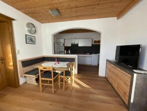 Eine kleine Küche mit weißen Schränken, einem eingebauten Backofen und einem Fernseher auf einer Arbeitsfläche.