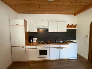 A compact kitchen with white cabinetry, a stove, a sink, and a dishwasher. - Apartment 2-5 people - Apartment Schranz (Kaunerberg)