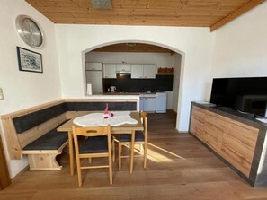 A compact kitchen with a dining area, wooden flooring, and a TV. - Apartment 2-5 people - Apartment Schranz (Kaunerberg)
