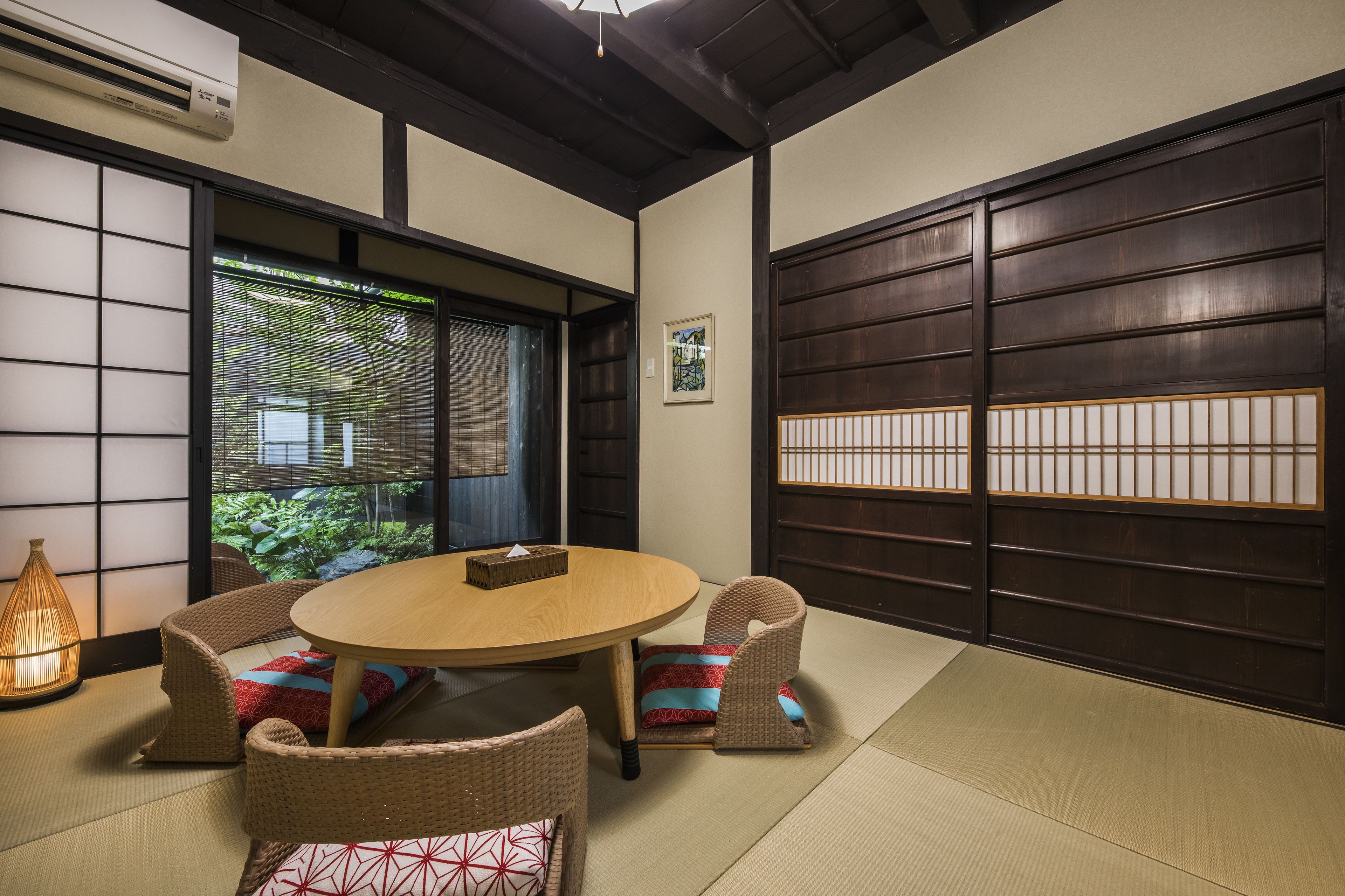 A traditional Japanese room with tatami flooring, a round wooden table, and low wooden walls.