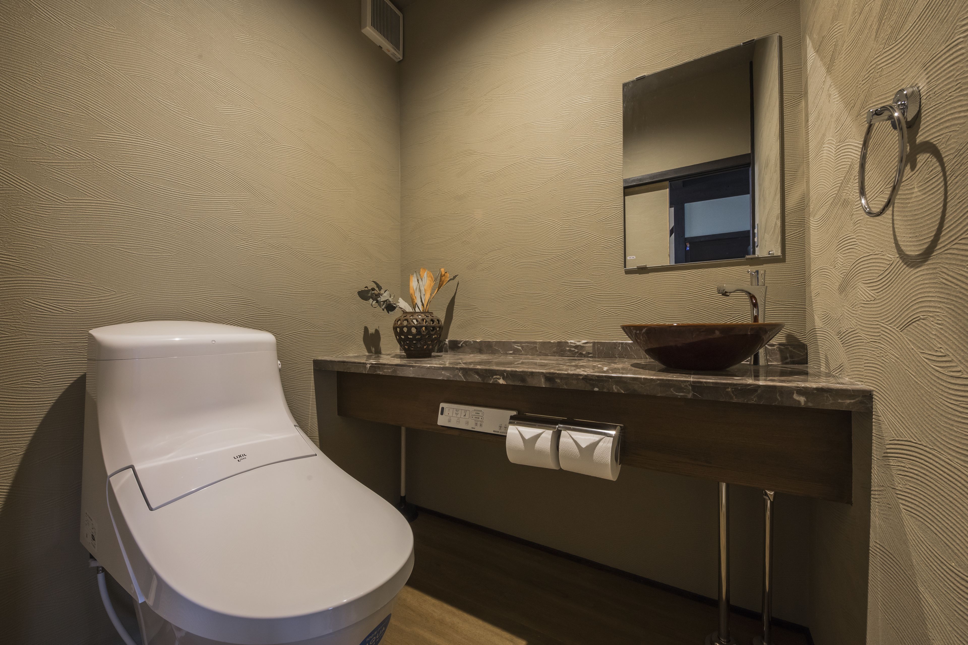 A modern bathroom with a white toilet, a marble sink, and a towel rack.