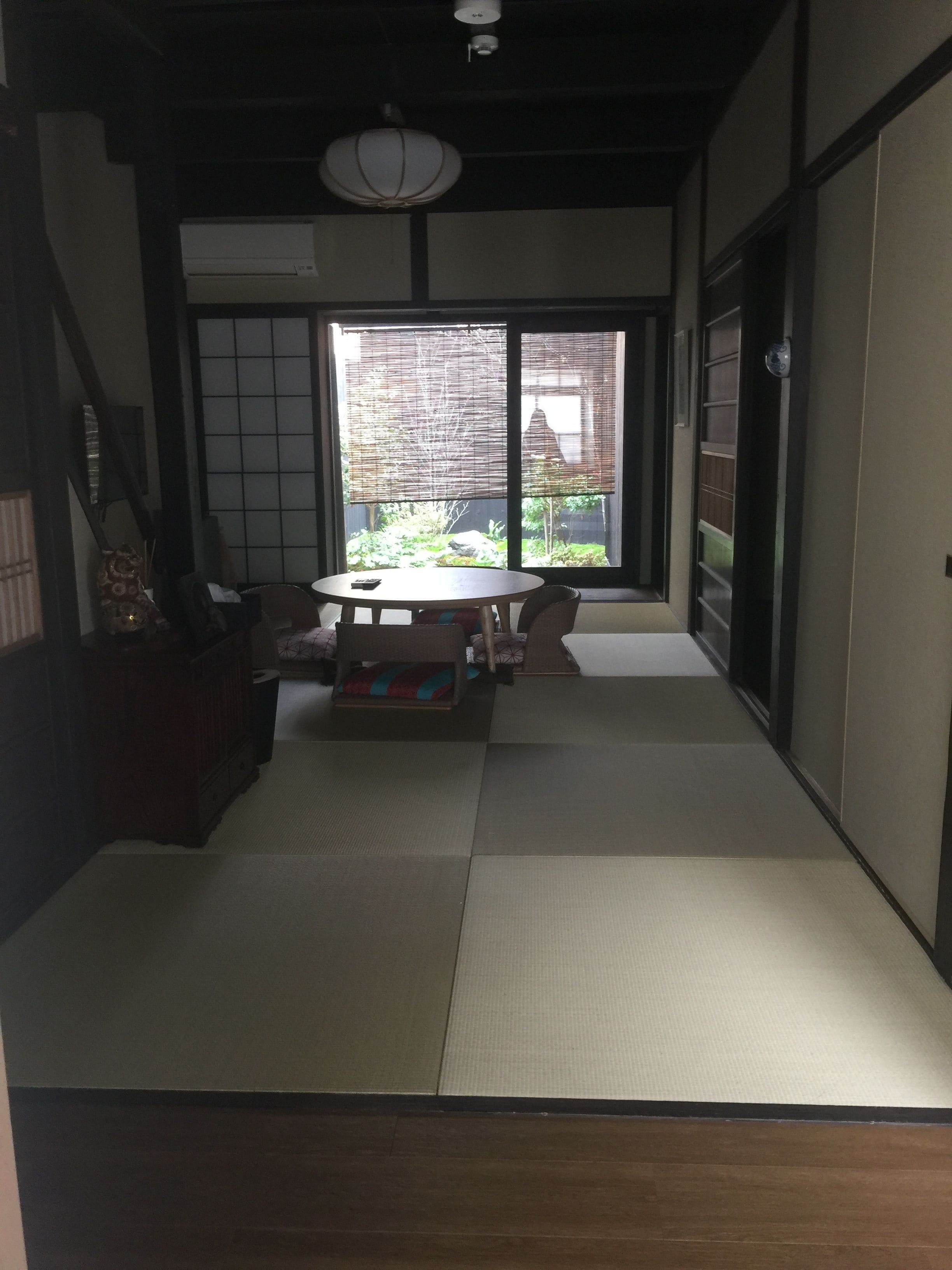 A traditional Japanese room with tatami flooring, a low table with cushions, and sliding doors.