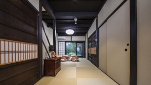 En traditionell japansk inredning med tatamimattor på golvet, ett lågt bord med kuddar och skjutdörrar.