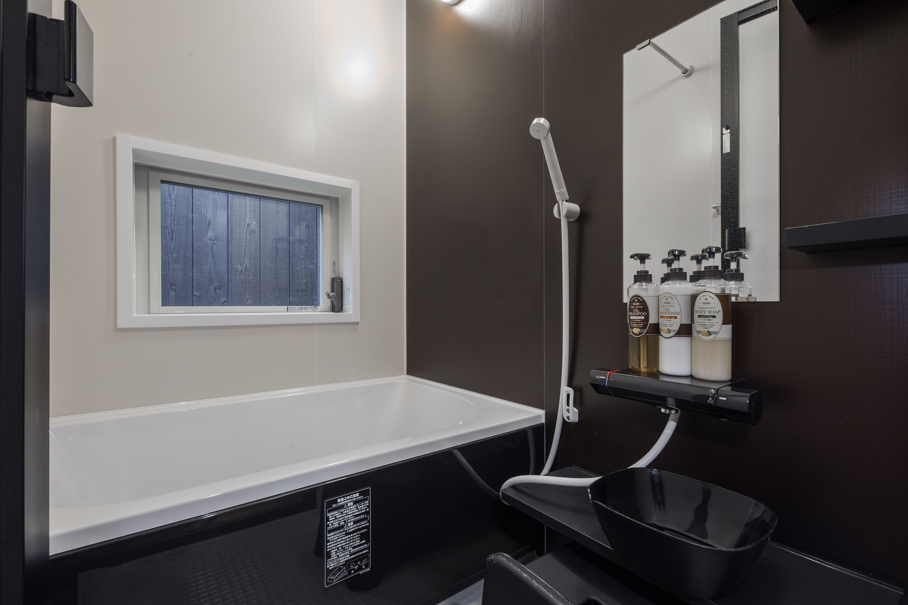 Un baño moderno con una bañera blanca, una ventana, ducha y un estante con artículos de aseo.