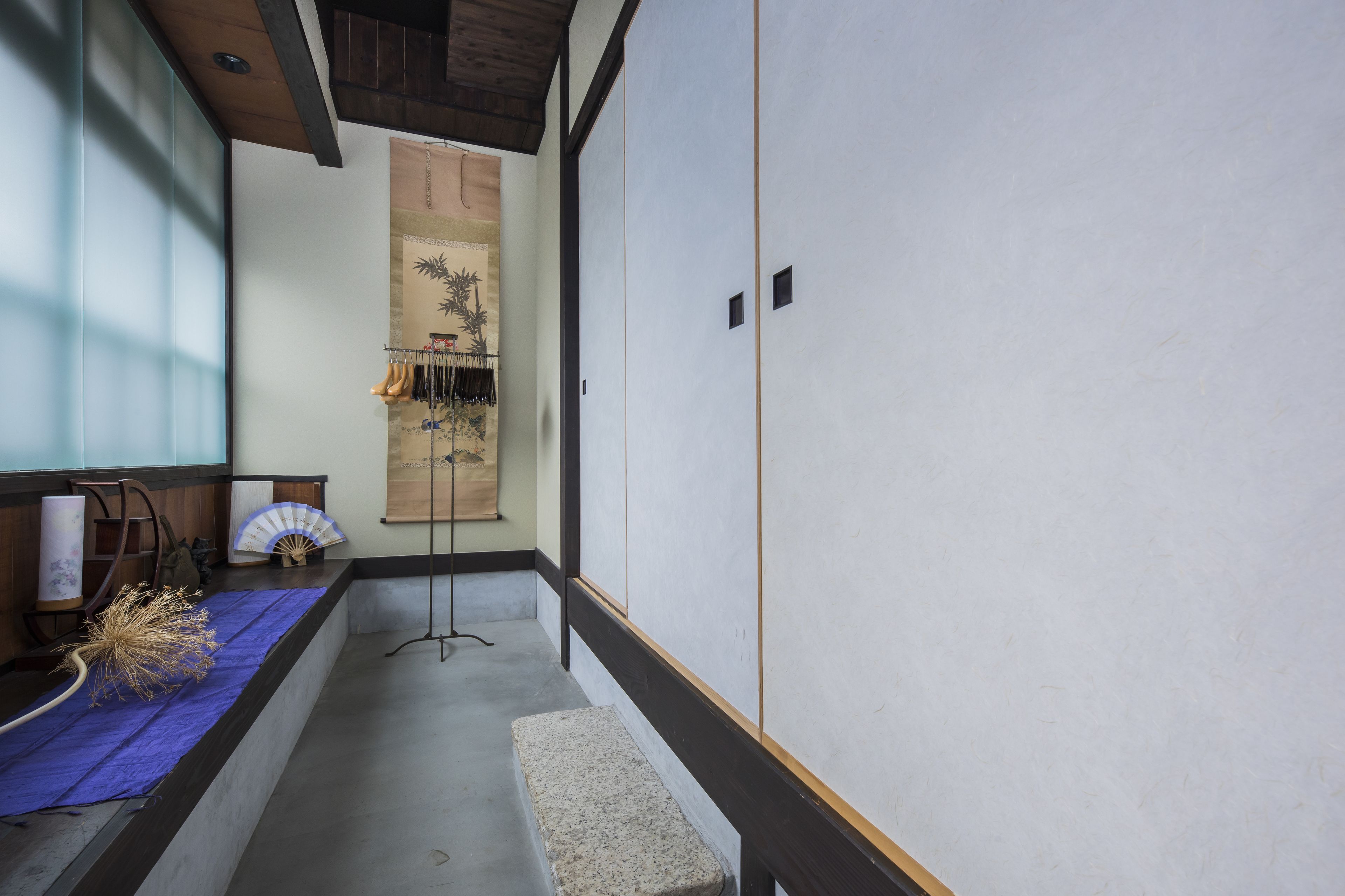 A traditional Japanese room with tatami flooring, a shoji screen, and a hanging fan.