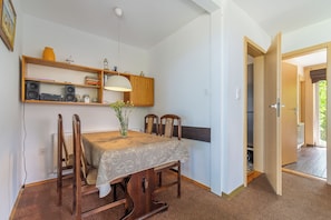 A dining area with a table, chairs, a lamp, and a bookshelf. - Vacation bungalow with a stunning ocean view for 2 to 4 people, (Pobierowo)
