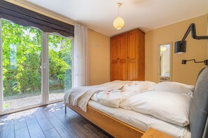 Un dormitorio con cama, ventana, armario y lámpara en el techo.