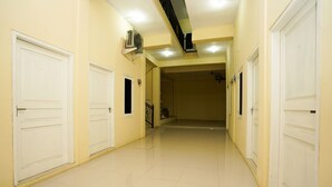 A hallway with white doors, a tiled floor, and an air conditioning unit mounted on the wall. - OYO 998 La'ana Residence Syariah (Surabaya)