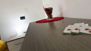 Ein Raum mit einem Holztisch, einem Glas mit Untersetzer und einem Kartenset auf dem Tisch.