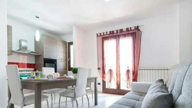 Eine moderne Wohnung mit Essbereich, Küche und einem großen Fenster mit Vorhängen.