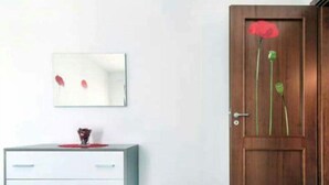 Ein Zimmer mit Holztür, einer weißen Kommode mit Schubladen und einem gerahmten Bild an der Wand.