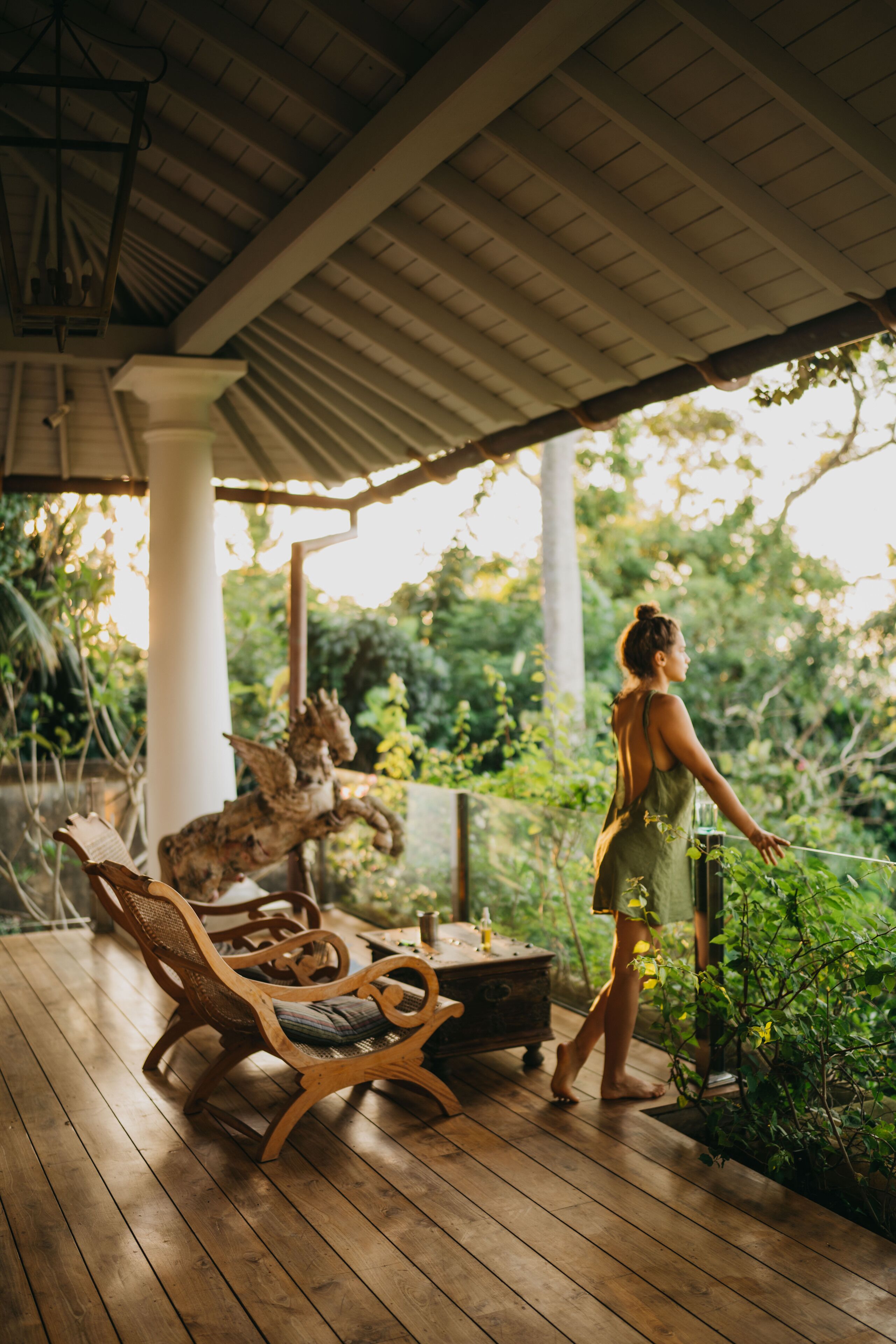 Une terrasse en bois avec un espace abrité, une statue et une femme en robe.