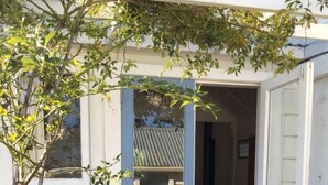 Un edificio bianco con porta e finestre azzurrine, circondato da fiori gialli.