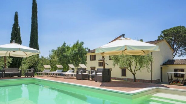 A swimming pool with lounge chairs and umbrellas, surrounded by trees and a building. - Villa Beboli per 18 pax by Interhome (Vinci)