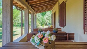 A covered outdoor seating area with wooden benches and a floral arrangement. - Villa Beboli per 18 pax by Interhome (Vinci)