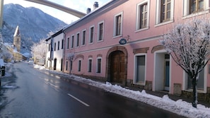 Ein pinkfarbenes Gebäude mit großem Bogenportal, einem gut sichtbaren Schild und einer verschneiten Straße.