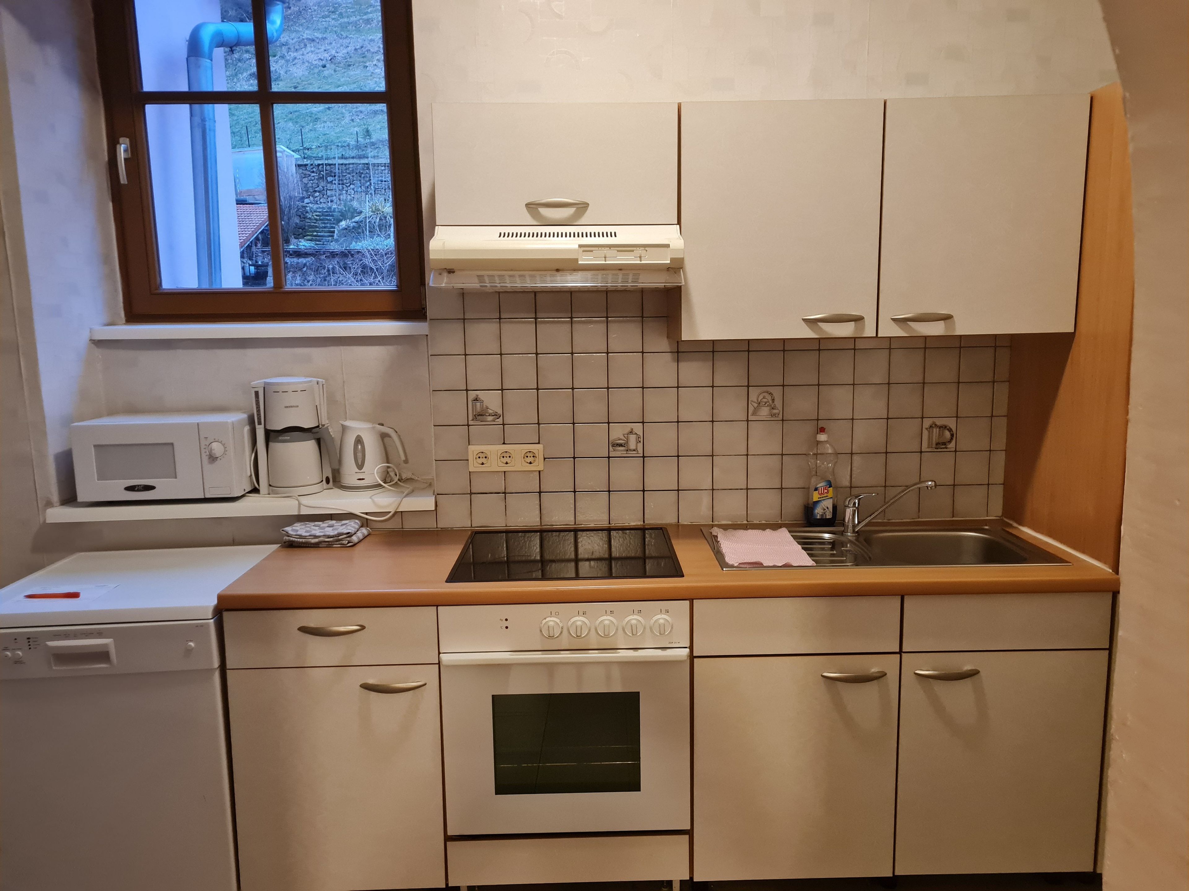 A compact kitchen with a microwave, coffee maker, and a sink.