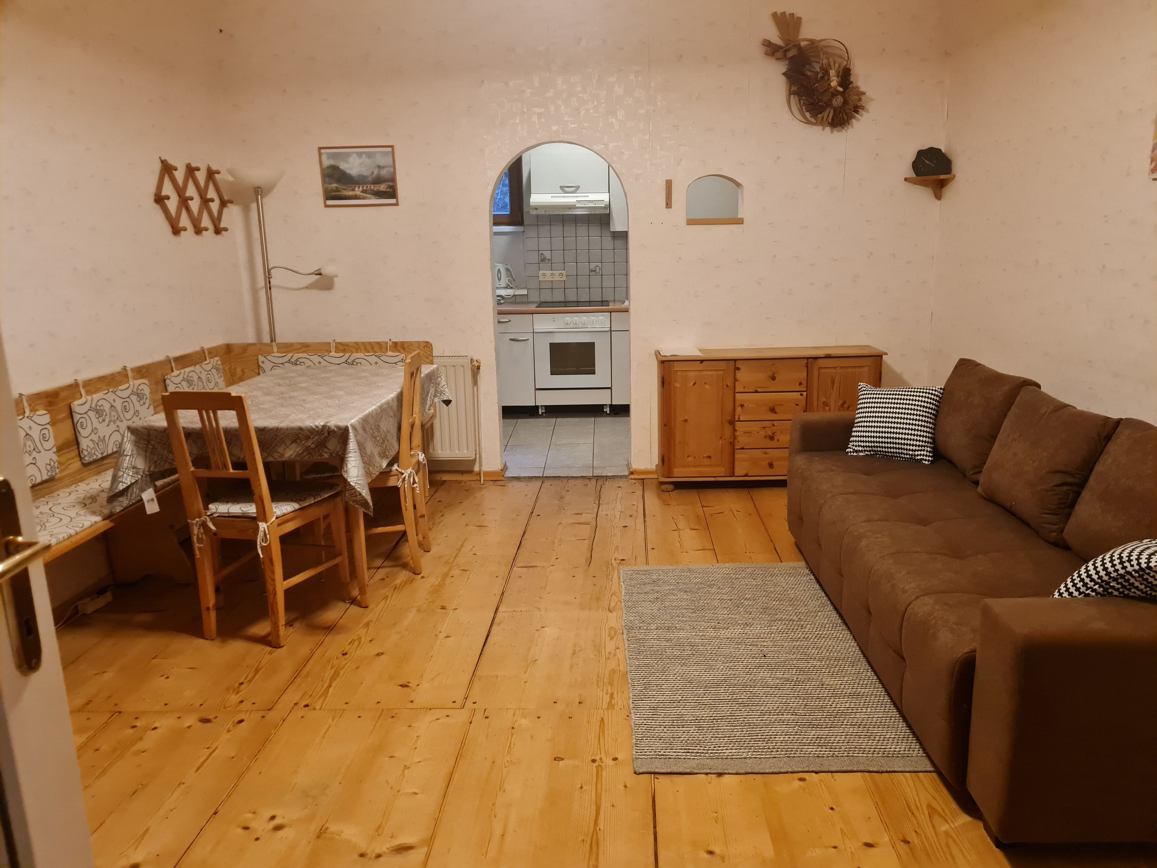 Ein gemütliches Wohnzimmer mit braunem Sofa, Esstisch aus Holz und Stühlen.