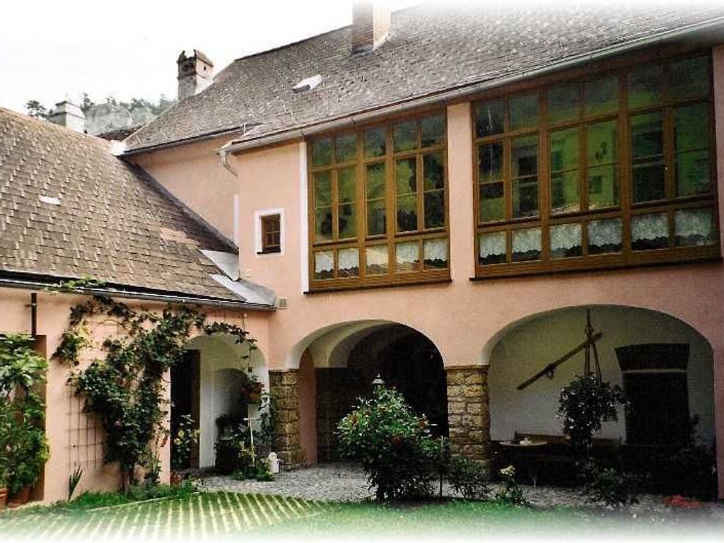 A building with a large arched window, a stone wall, and a small garden area.