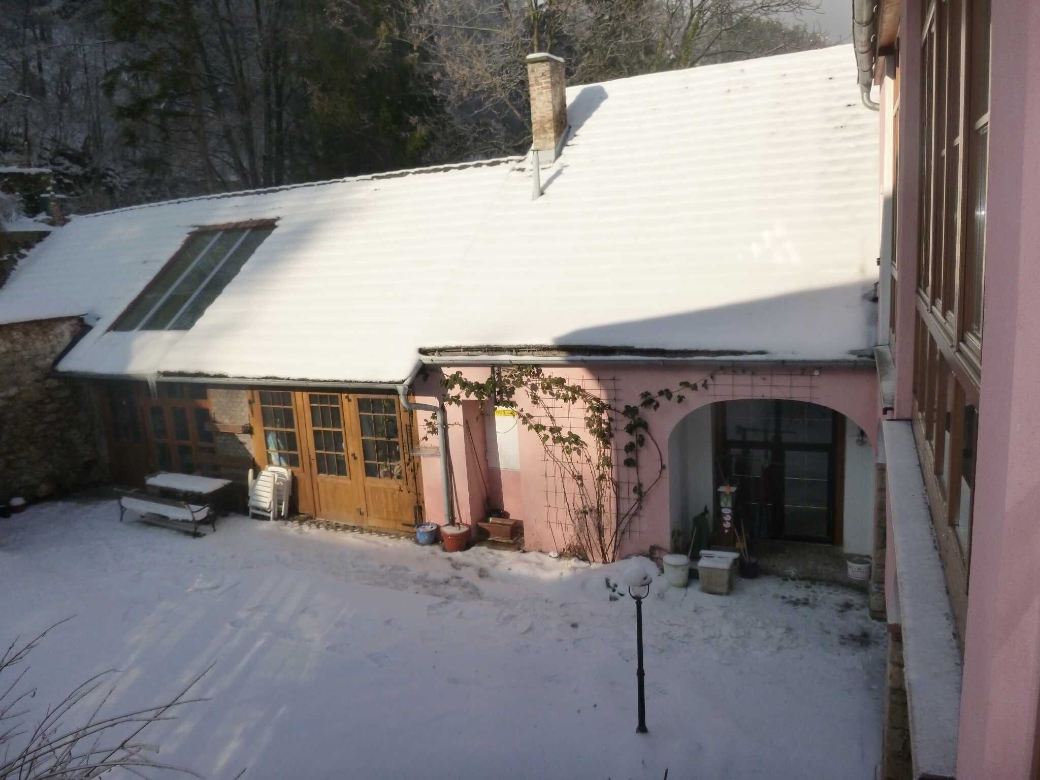 Et hus med sneklædt tag, en trædør og en lille veranda.