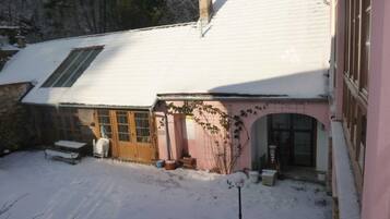 Et hus med sneklædt tag, en trædør og en lille veranda.