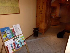 A room with a wooden floor, a map on the wall, a wooden cabinet, and a black cat on the floor.