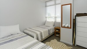 Un dormitorio con dos camas, una mesita de noche de madera, un espejo y una alfombra con estampado de cebra.