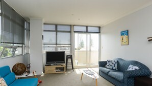 Una sala de estar moderna con un sofá azul, una televisión y una mesa de centro.