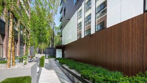 Um edifício moderno com um caminho reto e bem cuidado, ladeado por vegetação, e uma bicicleta estacionada ao lado.