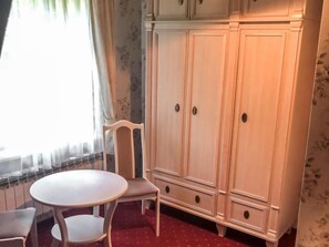 A room with a white wardrobe, a round table, and a chair. - Zielona Dolina Młyn by Interhome (Kwilcz)