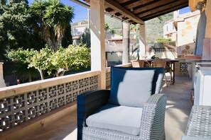 Zona relax all'aperto coperta, con mobili in vimini e vista su un quartiere residenziale con palme e case.