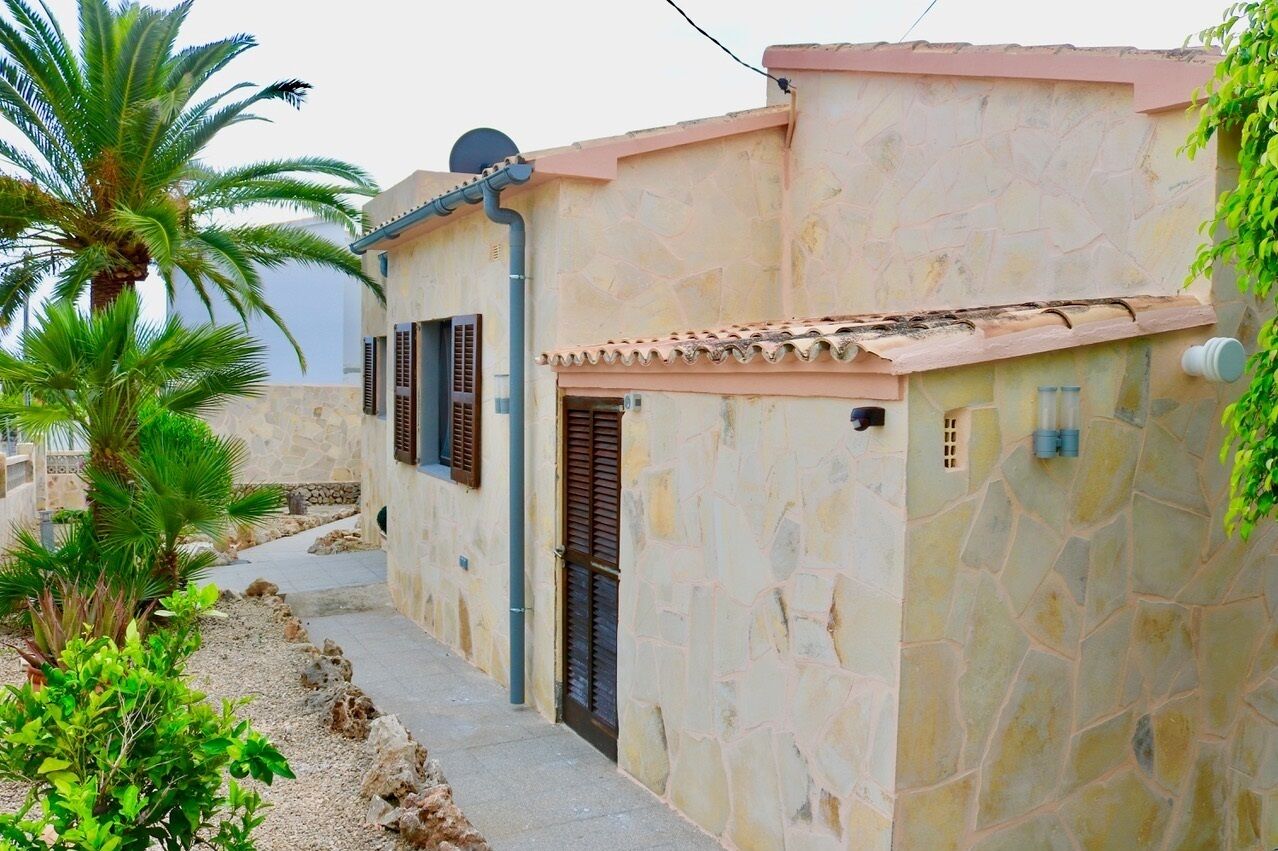 Un bâtiment en pierre avec un toit recouvert de tuiles, une porte et une petite fenêtre.