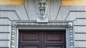A detailed architectural entrance with a decorative stone carving above a dark wooden door. - The Right Place (Rome)