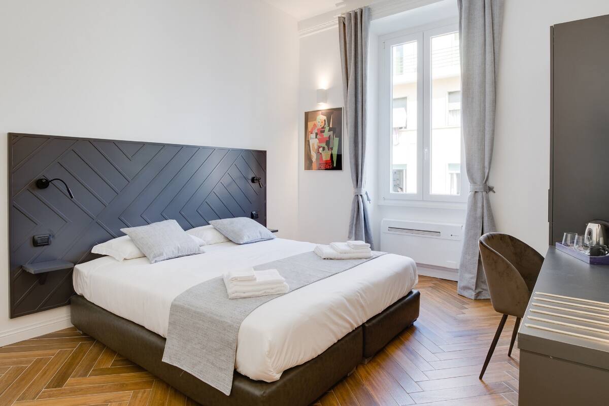 Una camera da letto moderna con un letto grande, una scrivania e una finestra con tende.